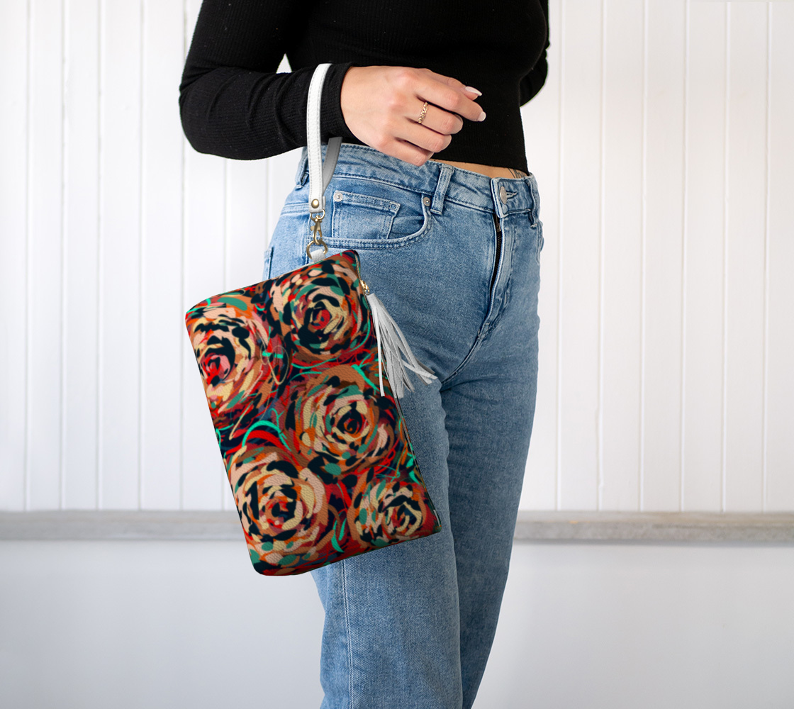 Blythe Collection Vegan Leather Makeup Bag in Floral, worn on wrist. This chic makeup bag features a wristlet strap for effortless portability, making it the perfect accessory for any on-the-go beauty lover