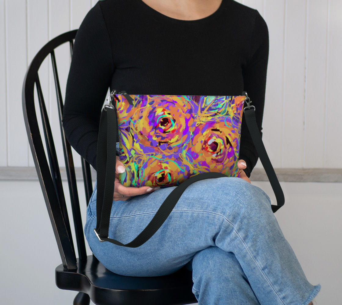 Cordelia Collection Vegan Leather Crossbody Purse in Floral, sitting in lap view. With its bold floral design and high-quality vegan leather, this purse offers style and convenience. The durable navy blue twill lining adds sophistication to this functional accessory.