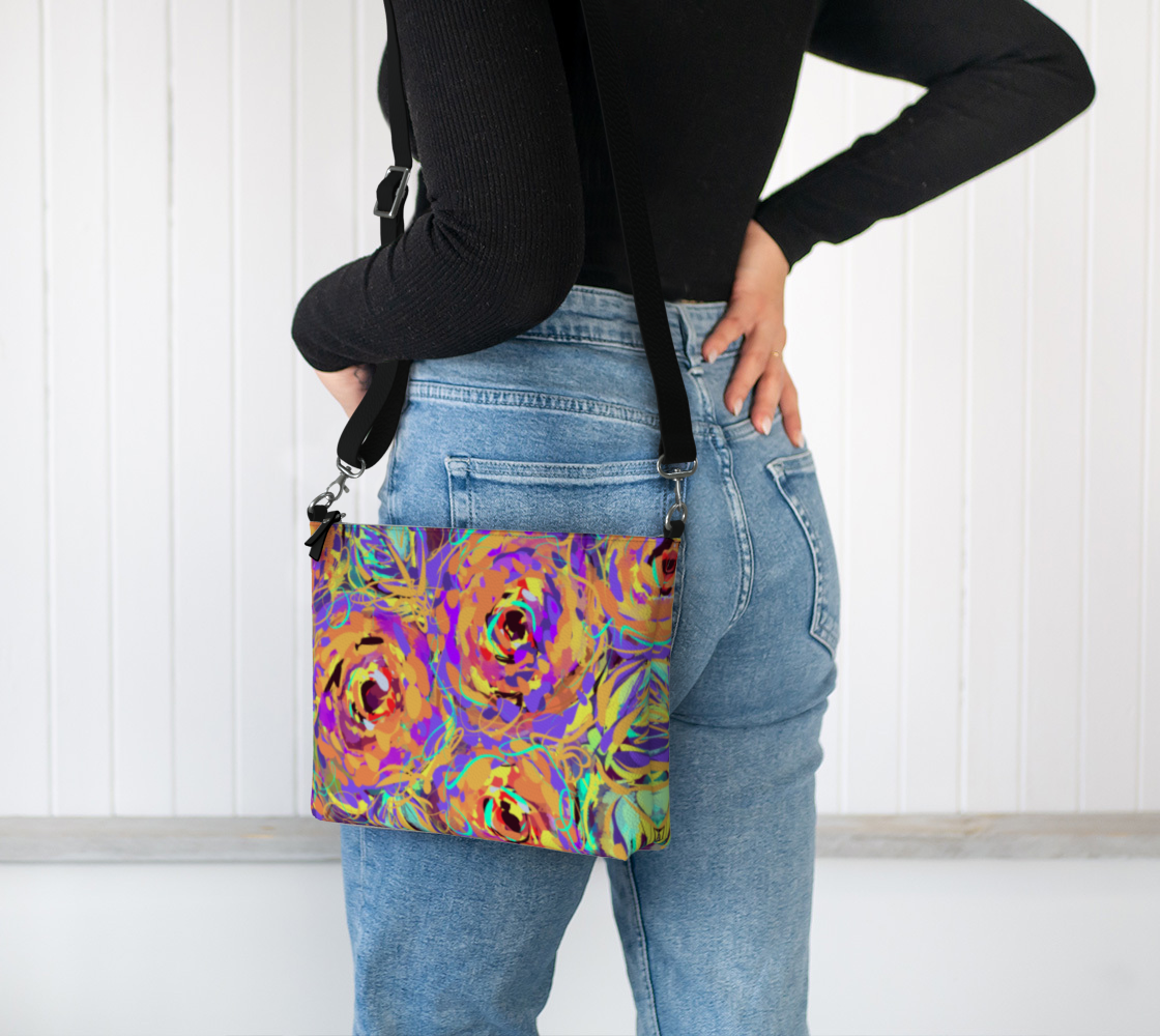 Cordelia Collection Vegan Leather Crossbody Purse in Floral, worn on shoulder. This eco-friendly purse, crafted from textured vegan leather, features vibrant rose patterns in purple, yellow, and blue. The adjustable shoulder strap provides comfort and versatility, making it an ideal accessory for any occasion.