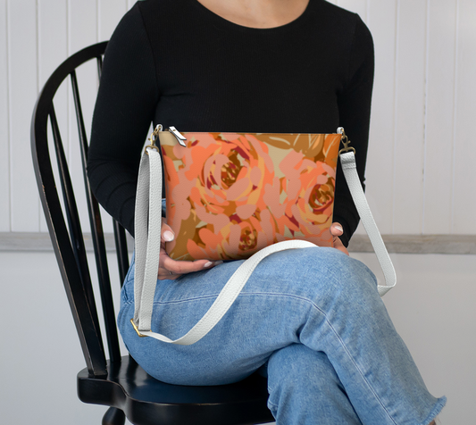 Queen of Petals Copper Sunset Vegan Leather Crossbody, sitting in lap, showing compact 8.5 by 7 inch size