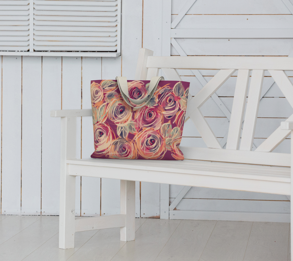 Zenith Rose Sovereign Tote Bag sitting on an outdoor bench, showcasing vivid hand-painted coral and berry roses, durable cotton webbing straps, and bold oversized structure. A floral shoulder bag designed to carry your world with fierce style and strength.